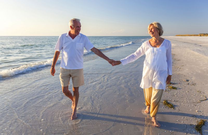 Elderly couple walking the shoreline at sunset